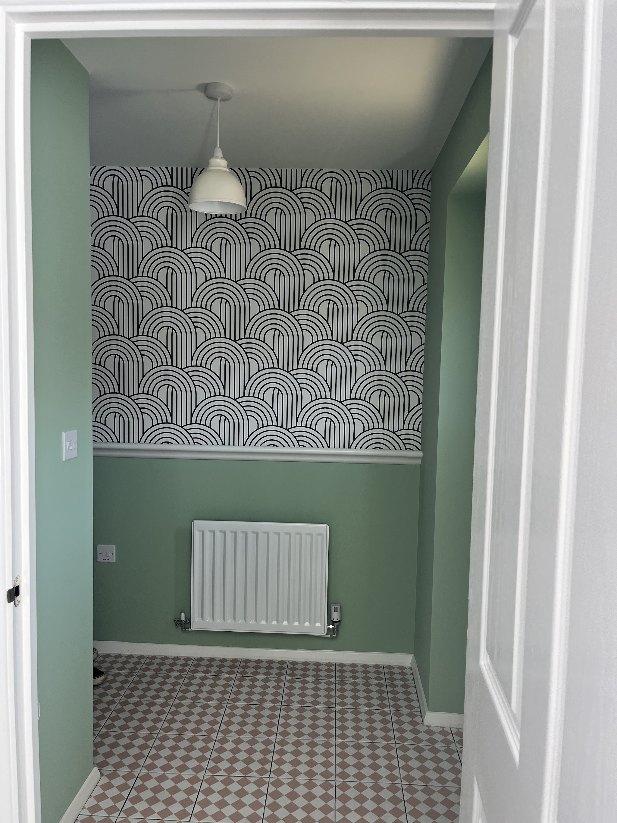 Small room in sage green with an arched pattern feature wallpaper