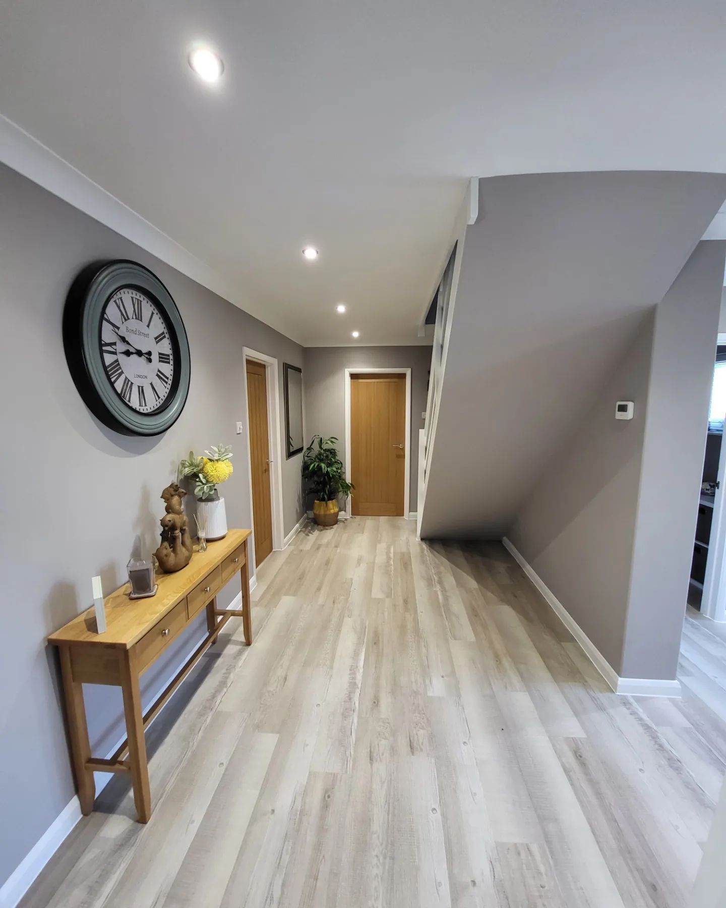 Light grey hallway with white skirting, oak doors and a console table