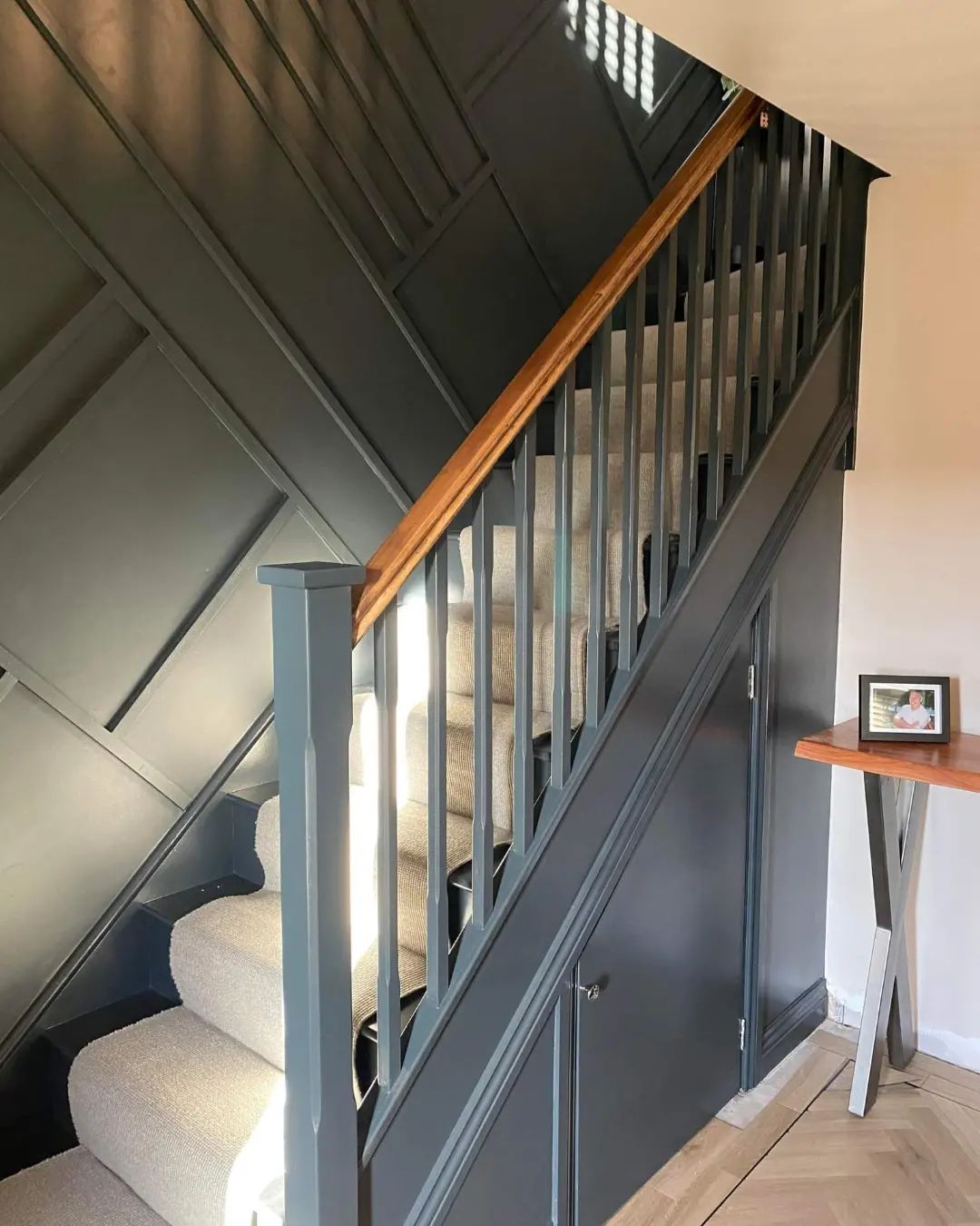 Staircase decorated in deep green with panelled wall and oak handrail