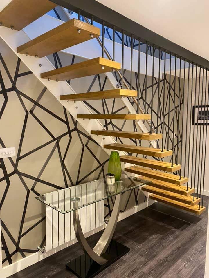 Floating oak staircase in front of a black and white geometric feature wall