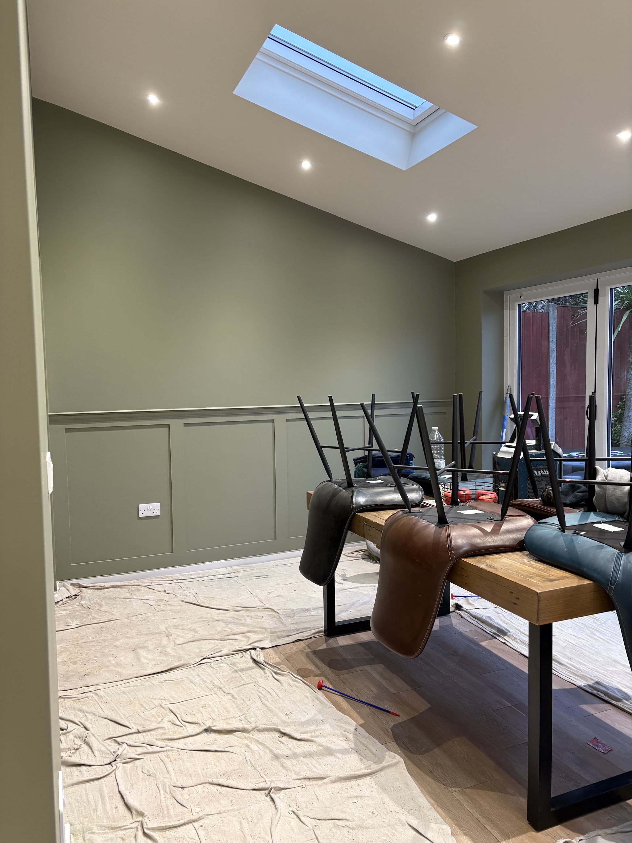 Dining room mid-job with olive green panelling, dust sheets down and furniture protected